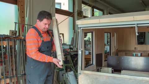 A middle-aged man is designing a car cabin. He is making a brand new wooden vintage car.