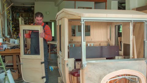 A joiner is bringing new wooden car door and he is going to put them on the car.
