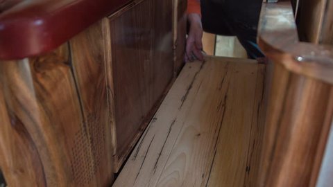 A woodworker is making sure the wooden floor in the vintage car that he is making is even and that there are no bumps.