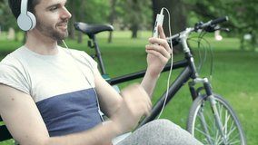 Handsome man watching something on tablet in the park and looks happy, steadycam shot
