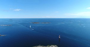 Speedboats on baltic sea, Cinema 4k aerial landing view towards a motorboat bypassing sailboats, out on the turquoise sea, on hango regatta day, in the finnish archipelago of Hanko, Finland