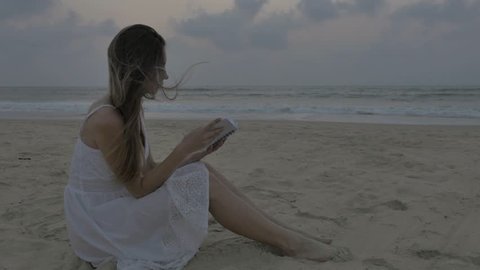 Worried  woman reading a notebook on the beach