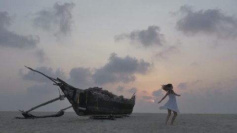 Cheerful young woman dancing on the beach