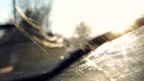 Fluid spraying on a windshield and wipers cleaning it off, in slow motion