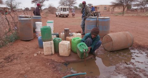 Poor people in Africa unable to maintain social distance due to water crisis. People collecting water in containers from a communal tap due to severe drought in South Africa