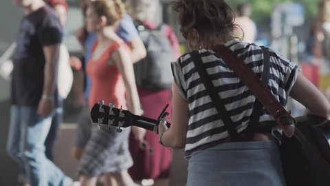 Unidentifiable Young Woman Playing Guitar On A Busy Shopping Street In Berlin In Summer. Slow Motion Shot.