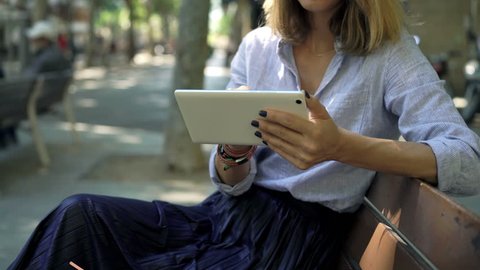 Businesswoman using tablet computer sitting on bench in city 
