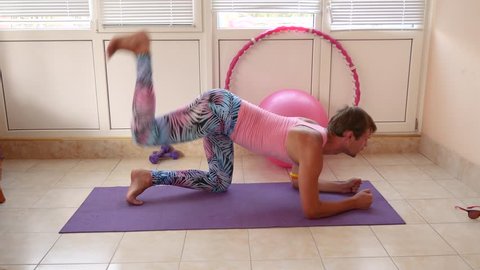 A playful handsome guy in a pink T-shirt and blue leggings is engaged in fitness depicting a girl. Slow motion