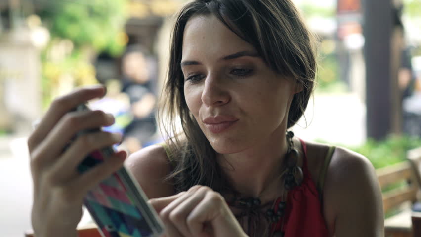 Young woman texting on smartphone sitting in cafe in city
