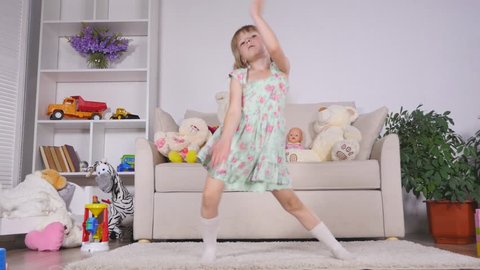 A little girl, adorable young talented dancer does ballet poses and stretching exercises on the floor at home.