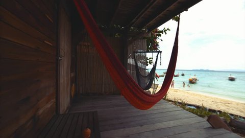 Two hammocks in wooden bungalow terrace and great white sand beach on the background. Ko Lipe island, Thailand