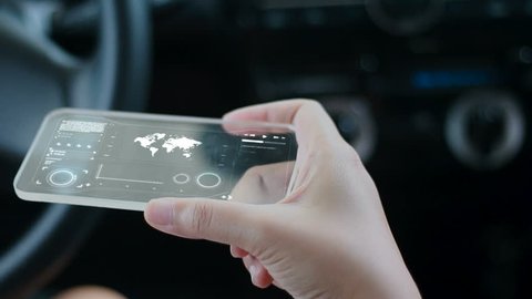 Close up shot hands of woman using clear glass smart phone in the car for futuristic cyber technology concept