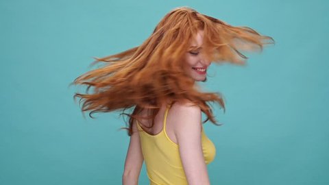 Young pretty girl with long red hair shaking her head isolated over blue background