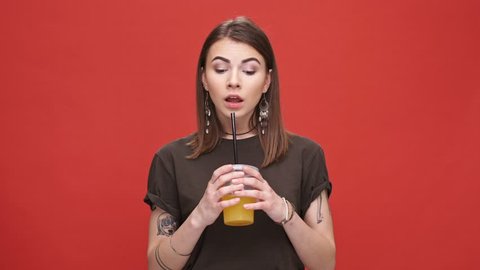 Young pretty girl drinking orange juice with bad taste isolated over red background
