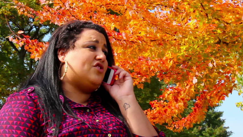 A young woman talks on her cell phone in the park.