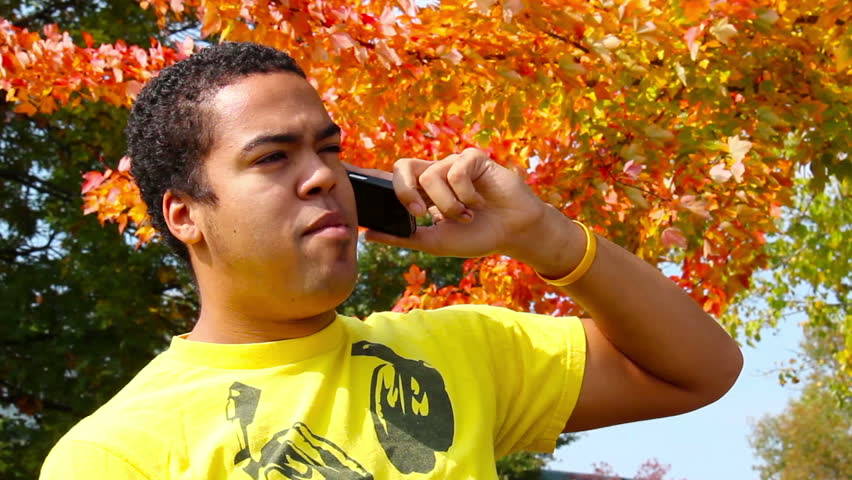 A young man talks on his cell phone in the park.