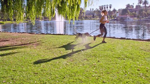 Attractive woman jogging with her dog in the park.