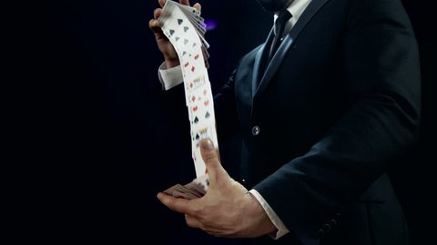 Close-up of a Magician's Hands Performing Card Trick. Throwing and Catching Cards in the Air. Background is Black. Slow Motion. Shot on RED EPIC-W 8K Helium Cinema Camera.