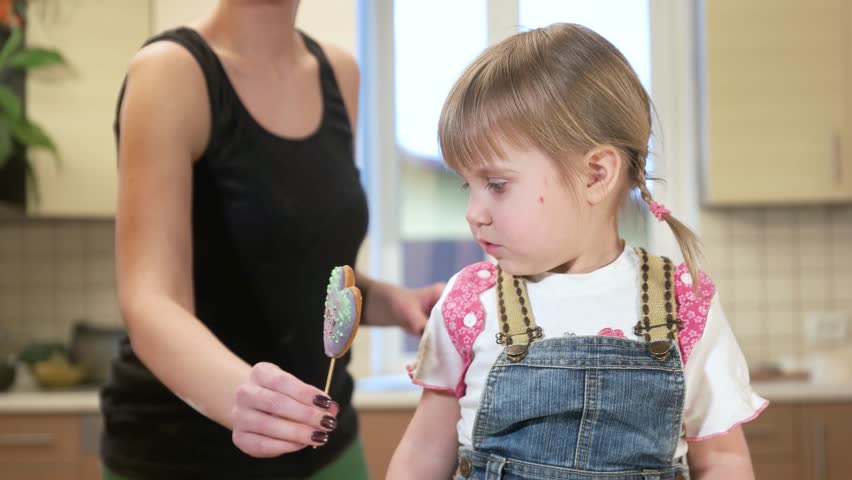 Daughter with mom in the kitchen eating a cookie