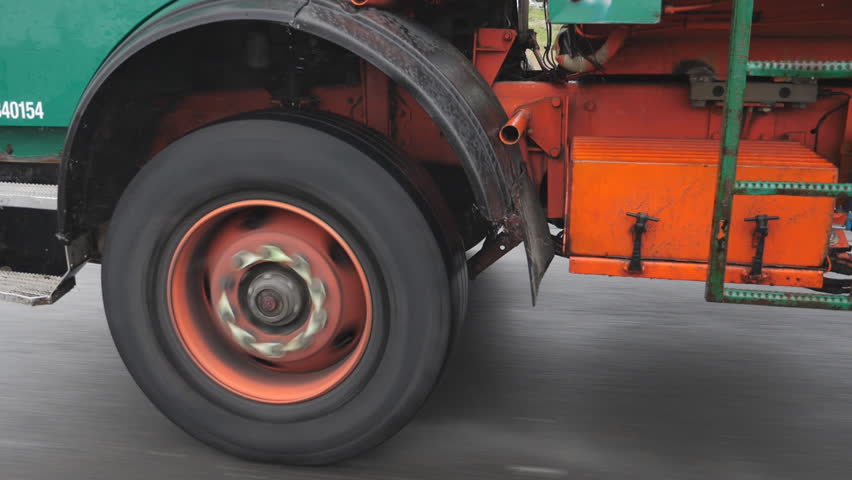 Slow motion shot. Truck wheel spinning on commercial orange and green truck in the rain. Drops of water splashing and coming off tire and mudguard.
 Royalty-Free Stock Footage #28901635