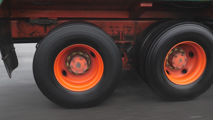 Slow motion shot. Truck wheels with orange hubs, spinning on commercial truck in the rain. 
 Royalty-Free Stock Footage #28901647