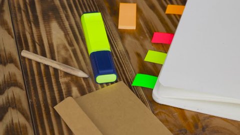 Woman write notes in notepad . Open notepad with office supplies. Open notepad lies on a wooden desktop with marker, pencil, pen and Stickers