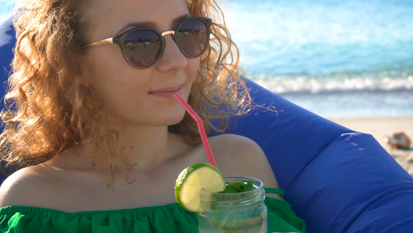 Young woman enjoying a tropical mojito cocktail with fresh lime at the seaside