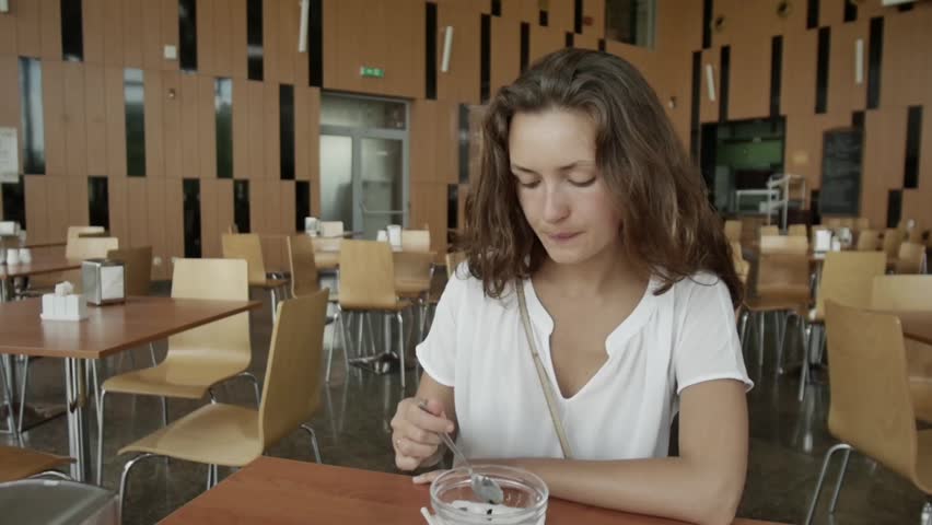The girl is having breakfast. Young girl in a cafe