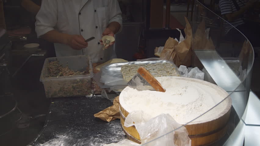 Local chef fills. assembles and prepares dumplings by hand in the kitchen of a Chinese restaurant in downtown Singapore. 4k footage