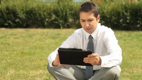 Young office worker with touchpad considering business options outdoors