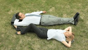 Relaxed office workers lying on the grass enjoying warm summer day