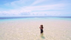 Aerial drone quad copter footage of young woman wearing virtual reality headset watching 360 travel video imagination concept in amazement and exploration on tropical beach exotic island. 