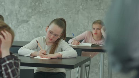 Students in school uniform taking exam at desk in a classroom