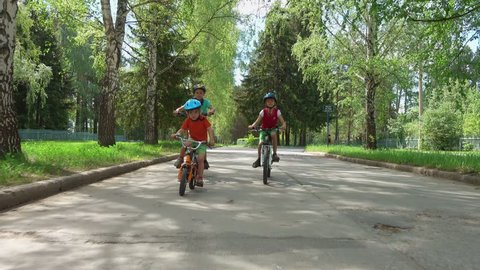 Three children riding bicycles during summer holiday. Brothers cycling on the road.
