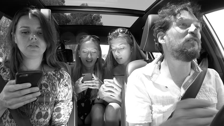 Man desperate about family not listening to him playing with cell phone in car black and white