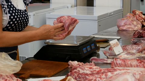 Close-up seller weigh meat when woman choose the meat from the counter at the market