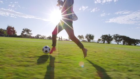 Four young adults playing football in a park at sunset Video Stok