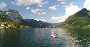 Beautiful woman in Bikini on a Stand Up Paddle Board on Lake Grundlsee in the middle of the Austrian Alps.
