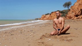 Young Yoga man doing Flexible Exercise on the deserted Wild Sea Beach