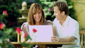 Young Caucasian couple at leisure using wireless technology in garden smiling and planning on laptop computer RED EPIC