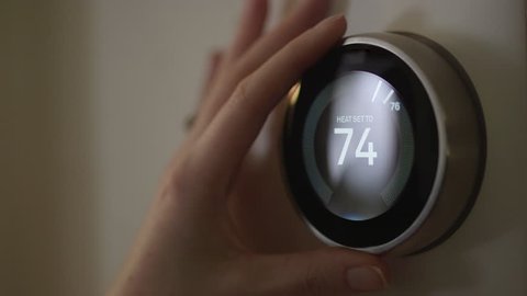Woman Adjusting Smart Thermostat Gadget At Home