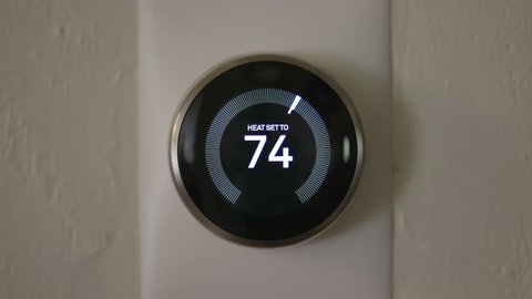Man Increasing Temperature of Smart Thermostat Gadget At Home