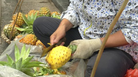 close up of a woman cutting pineapples on the street in the old quarter of hanoi, vietnam