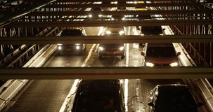 Slow motion shot over cars driving under bridge at night.