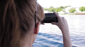 Girl shoots video on camera phone during trip on the boat on the river