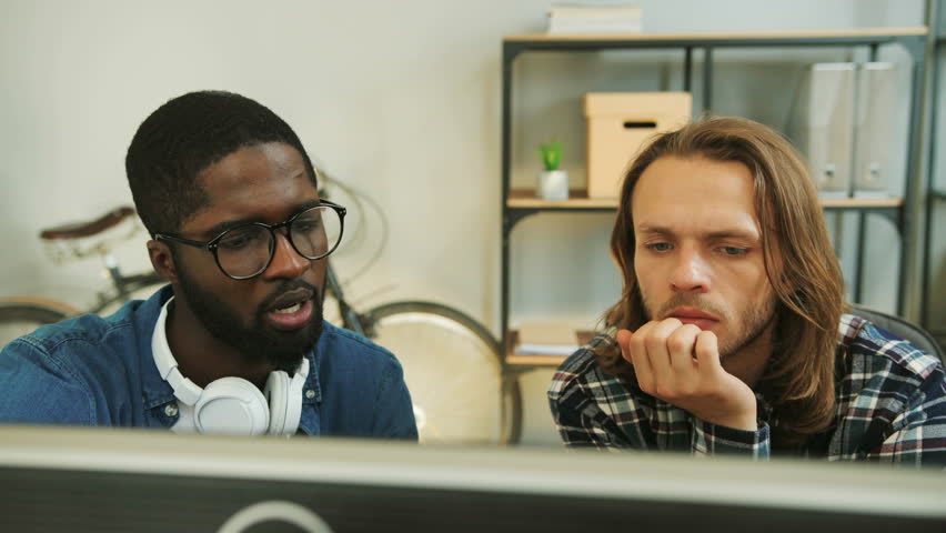 African business man explain his caucasian colleague information from the report in the laptop. Close up shot.