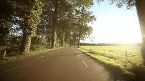 video footage of a on-board camera on a car driving on a country road in the sunset