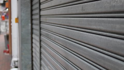 A steady close up shot of a bakery store closing its steel roller doors.