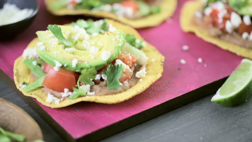 Fresh vegetarian Mexican tostadas on purple cutting board.