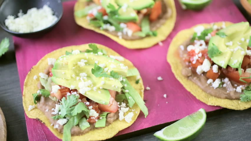 Fresh vegetarian Mexican tostadas on purple cutting board.